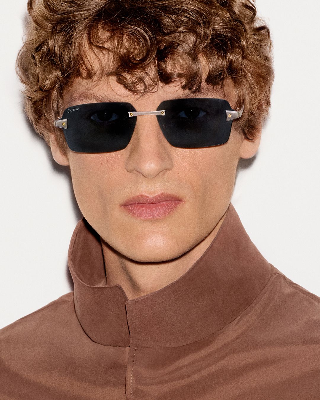 Model in rimless rectangular Cartier sunglasses and a high-neck brown top