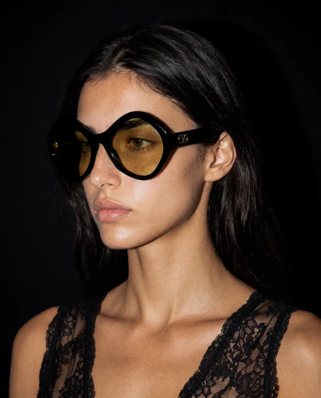 A model in round black sunglasses with amber lenses, autumn 2026