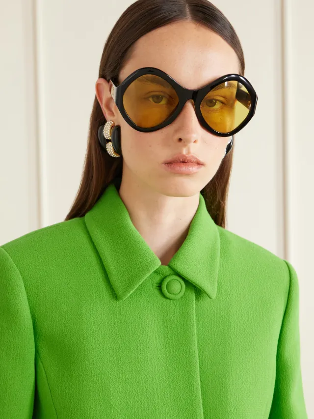 A model in round sunglasses with amber lenses